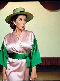 A curvaceous woman in pink kimono and hat stands center stage