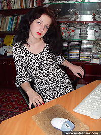 Brunette girl posing near computer with enigmatic smile