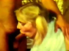 Bubblegum blow job : A young blond girl is laying on a bed with her tits bare. She is talking to a guy. A little later she is sucking his dick while another guy is fucking her at the same time. The she gets a load of sperm in her face.